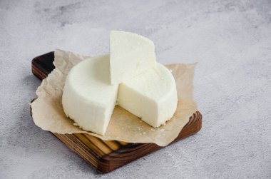Ev yapımı yumuşak peynir brynza ya da gri arka planda tahta kesim tahtasındaki feta. Yatay oryantasyon. Kapat.