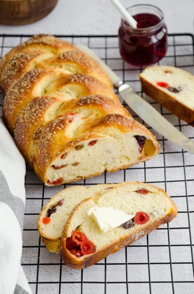 Traditional sweet Easter bread with raisins, dried cherries with jam and butter on a light background. Cozonac - Bulgarian Easter bread. Rustic style. Vertical orientation, close up.