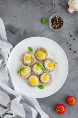 Beyaz bir tabakta bıldırcın yumurtalı mantar ve fesleğen ve kekik yapraklı koyu beton arka planda. Paskalya mezesi. Dikey oryantasyon. Üst görünüm