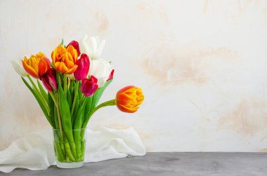 Cam vazodaki renkli doğal lalelerden oluşan bir buket. Beton zemin üzerinde su var. Anneler Günü tebrik kartı, Kadınlar Günü. Yatay oryantasyon. Boşluğu kopyala