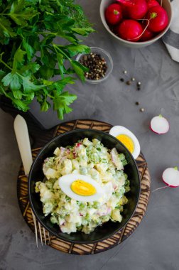 Patates salatası, turp, yumurta, bezelye, ekşi krema ve mayonez bir kase içinde koyu beton arka planda. Dikey oryantasyon. Üst görünüm, alanı kopyala