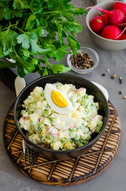 Patates salatası, turp, yumurta, bezelye, ekşi krema ve mayonez bir kase içinde koyu beton arka planda. Dikey yönelim, boşluğu kopyala