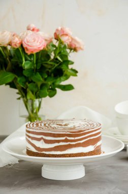 Beton zeminde beyaz bir tabakta vanilyalı ve çikolata kaplı fırında zebra mermer cheesecake yok. Dikey oryantasyon. Boşluğu kopyala