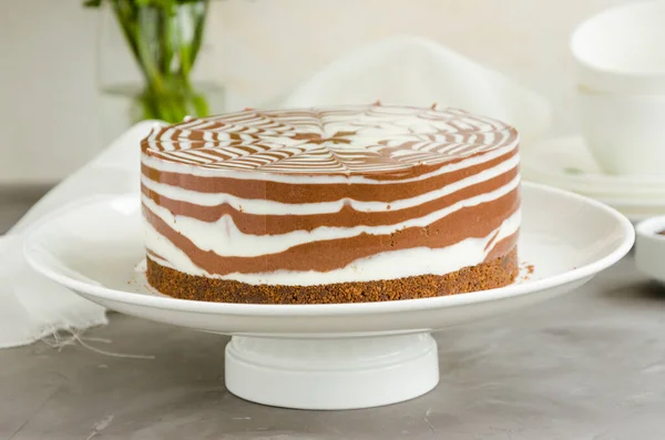 Beton zeminde beyaz bir tabakta vanilyalı ve çikolata kaplı fırında zebra mermer cheesecake yok. Yatay oryantasyon. Kapat..