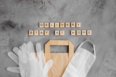 Ürünlerin teslimatı, evde yiyecekler. Koruyucu maskeli kağıt torba ve koyu beton arka planda eldivenler. Evde kal. Yatay, üst görünüm, boşluğu kopyala