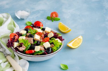 Ton balıklı salata, taze sebzeler, zeytin ve açık mavi beton arka planda beyaz peynir. Sağlıklı yiyecekler. Yatay oryantasyon. Boşluğu kopyala.