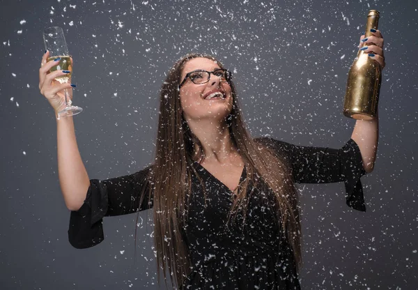 Beautiful woman celebrating New Year with confetti and champagne