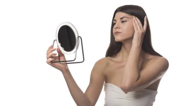 Bir ayna ile siting genç esmer kız. Güzellik kavramı. Beyaz arka plan üzerinde izole