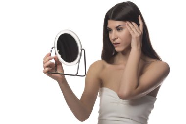 Bir ayna ile siting genç esmer kız. Güzellik kavramı. Beyaz arka plan üzerinde izole