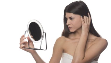 Bir ayna ile siting genç esmer kız. Güzellik kavramı. Beyaz arka plan üzerinde izole