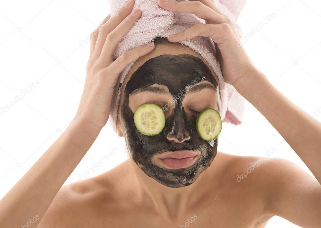 Beautiful girl with black facial cosmetic mask and cucumbers on eyes. Beauty concept. Isolated on white background