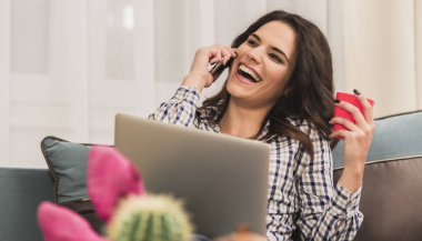 güzel esmer siting, cep telefonuyla konuşan ve bir dizüstü bilgisayarda aynı anda sohbet kanepe.