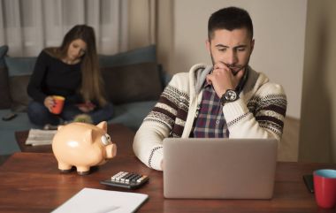 Genç adam evde dizüstü bilgisayar kullanıyor.