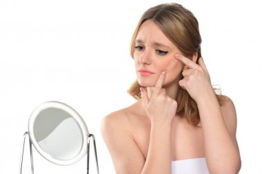 güzel genç sarışın bir kadın bir yama ile ayna önünde. Beyaz arka plan üzerinde izole