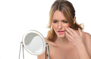 Güzel sarışın kadın diş ağrısı taklit bir ayna önünde. Beyaz arka plan üzerinde izole