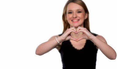 Kamera yapmak kalp işareti parmakları ile gözetleme genç güzel kadın portresi. Beyaz arka plan üzerinde izole