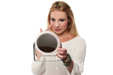 Aynada yüzünü kontrol eden bir kadın.