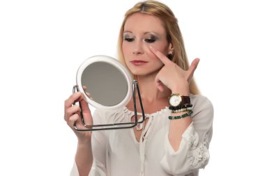 Aynada yüzünü kontrol eden bir kadın.