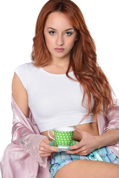 美しい魅力的な赤毛の女の子がお茶やコーヒーのカップを保持しています 白い背景に分離 — ストック写真
