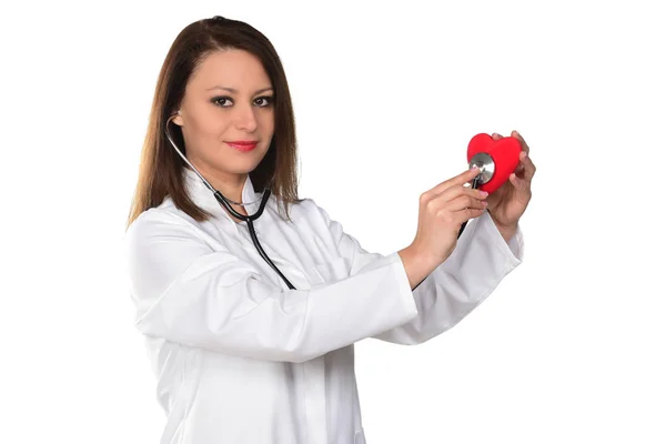 一个年轻的女医生用听诊器检查红色的心脏 孤立的白色背景 — 图库照片