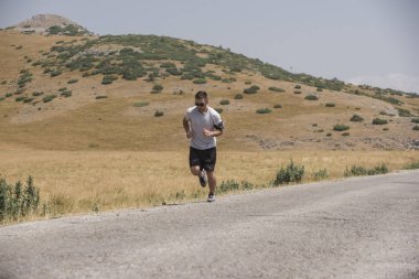 Erkek koşucu güneşin altında dağda koşuyor - sağlıklı yaşam tarzı kavramı