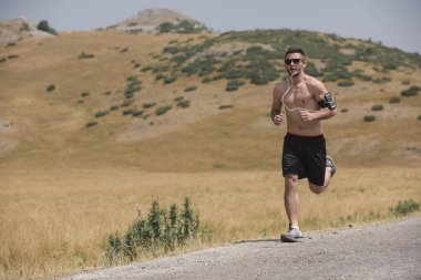 Erkek koşucu güneşin altında dağda koşuyor - sağlıklı yaşam tarzı kavramı