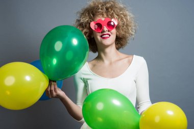 Balonlar tutan mutlu komik sarışın kadın