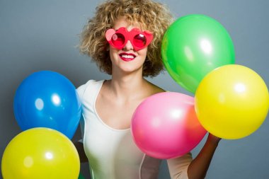 Balonlar tutan mutlu komik sarışın kadın