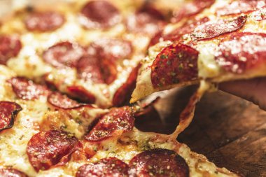 Peynir ve rustik ahşap bir masa üzerinde erime ile sıcak pizza