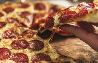 Peynir ve rustik ahşap bir masa üzerinde erime ile sıcak pizza
