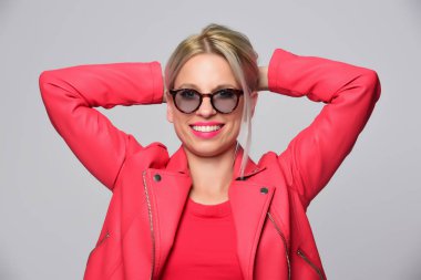 Stüdyo ışık arka plan üzerinde poz parlak deri ceketli genç kadın