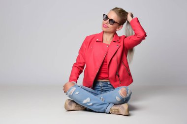 Stüdyo ışık arka plan üzerinde poz parlak deri ceketli genç kadın