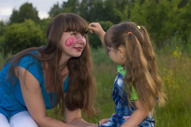 küçük kızı boya kalemi yüz anne üzerinde çizer.