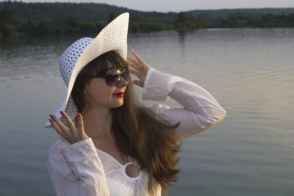 Белая женщина в солнцезащитной шляпе на пляже озера — стоковое фото