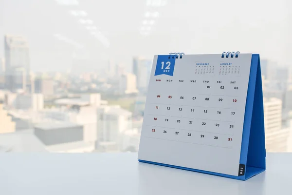Calendario de diciembre en la mesa blanca con vista a la ciudad de fondo —  Fotos de Stock