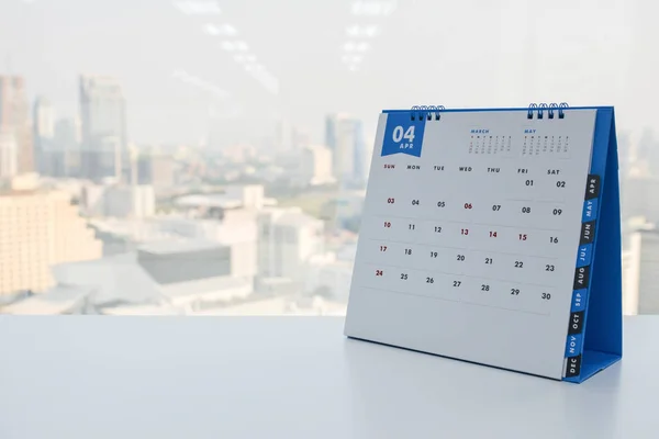 Kalendář dubna na bílém stole s výhledem na město pozadí — Stock fotografie