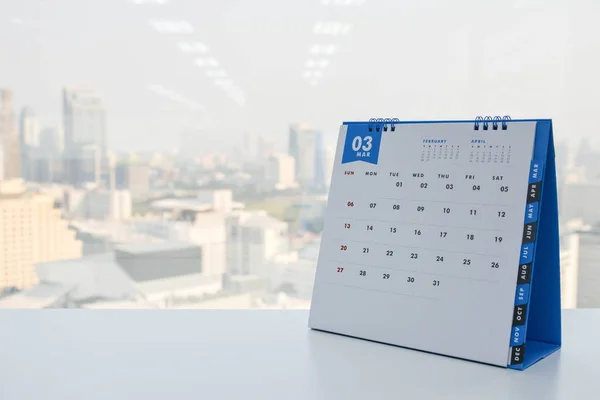 都市の景色を背景にした白いテーブルの上の3月のカレンダー — ストック写真