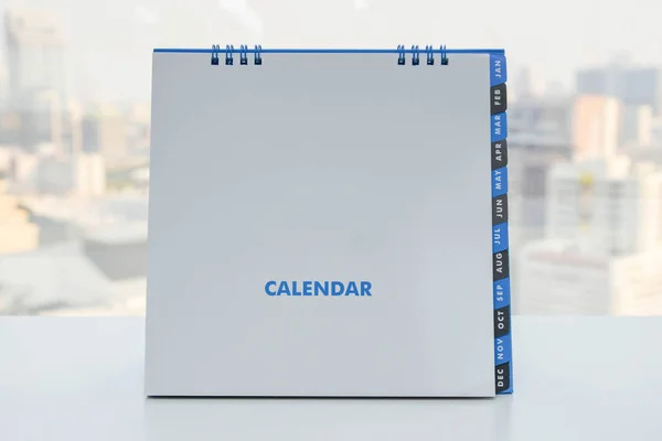 Kalendář na desku bílé město na pozadí — Stock fotografie