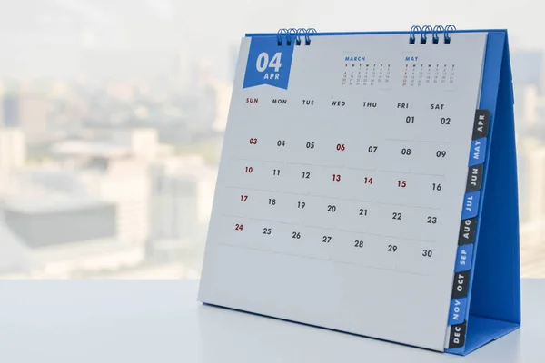 Primer plano - Calendario de abril en la mesa blanca con vista a la ciudad de fondo —  Fotos de Stock