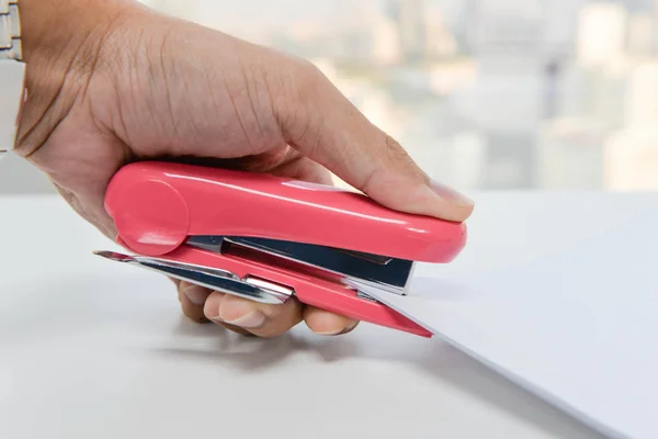 A mão humana está grampeando o papel com grampeador rosa — Fotografia de Stock