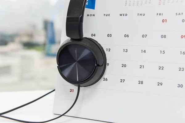 Auriculares negros sobre oreja en el calendario blanco — Foto de Stock
