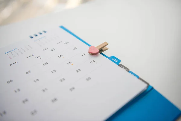 Calendário na mesa e clipe de coração rosa — Fotografia de Stock