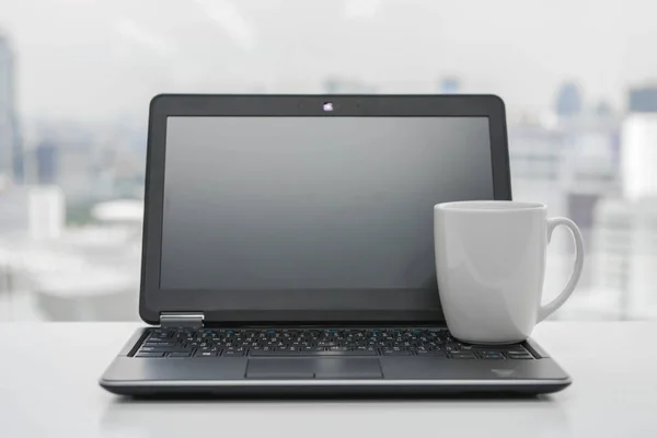 白咖啡杯子是黑色笔记本电脑上 — 图库照片