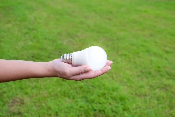 Led Lampe Mit Beleuchtung Frauenhand Mit Grashintergrund Für Energiesparkonzept — Stockfoto