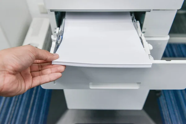 Human hand is reloading the paper to printer tray