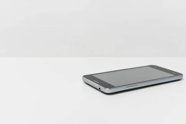 Schwarzes Handy auf dem weißen Tisch — Stockfoto