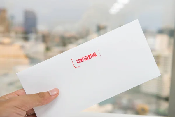 Рука держит белый конверт с красной конфиденциальной резины — стоковое фото