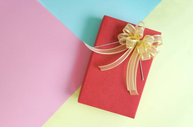 Renkli arka planda kurdeleli minimum kırmızı hediye kutusu düzlüğü