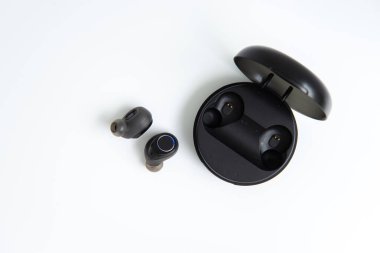 Tahta arka planda güç bankası kablosuz kulaklığı olan siyah bir kulaklık.