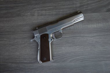Kahverengi elli paslanmaz tabanca ahşap zeminde. 